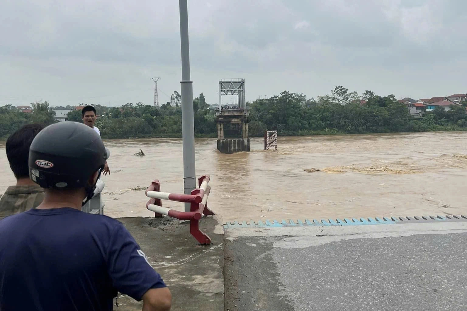 Người dân bàng hoàng đứng nhìn cây cầu sập trong nước lũ (Ảnh: Ngọc Nguyễn).