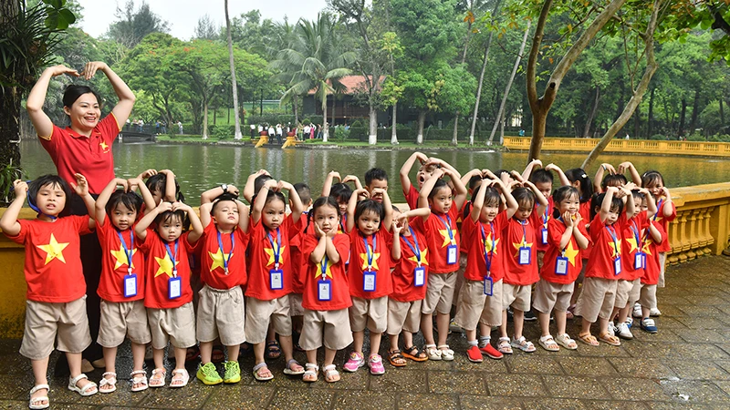 Cô và trò chụp ảnh kỷ niệm bên ao cá Bác Hồ trong Khu Di tích Chủ tịch Hồ Chí Minh tại Phủ Chủ tịch. (Ảnh ÐĂNG KHOA)